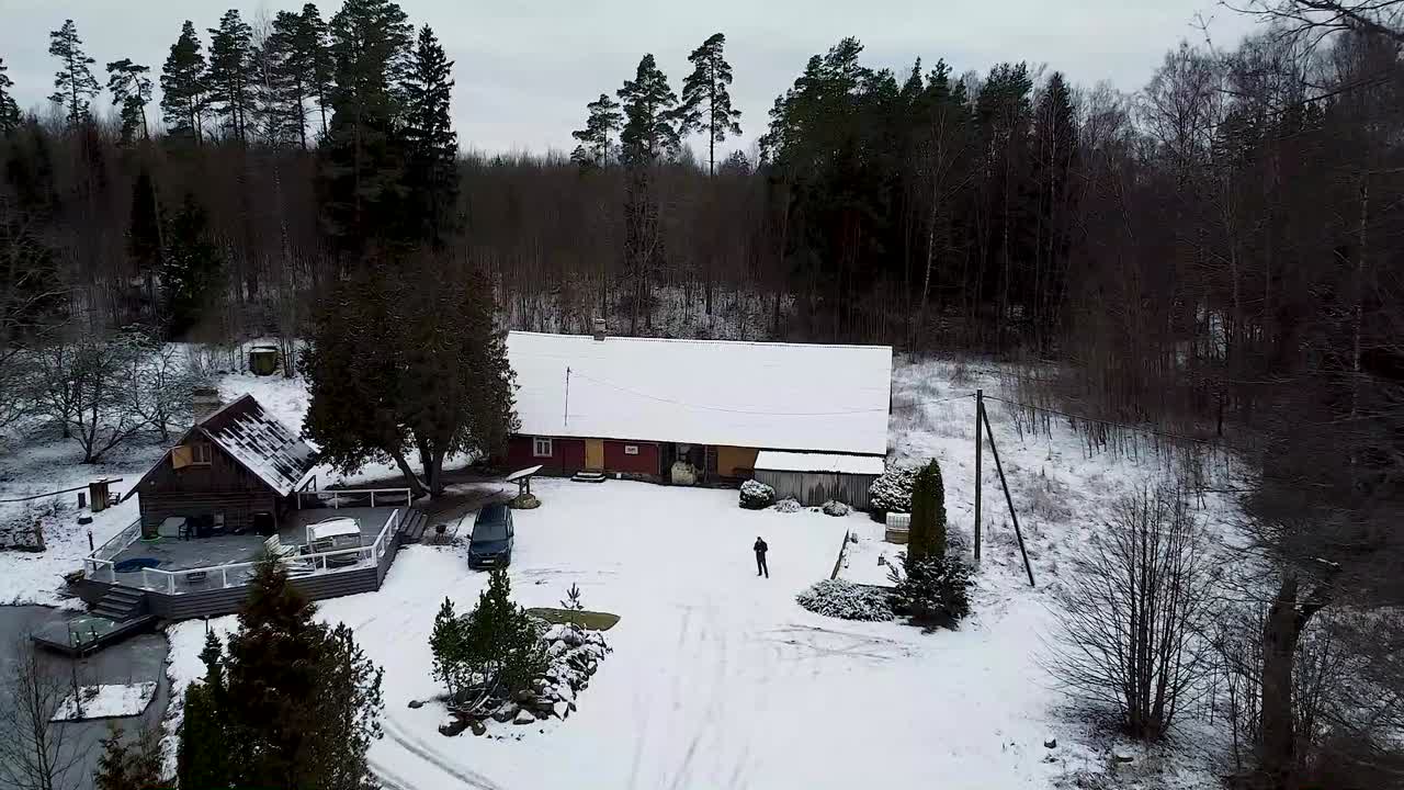 Aerial drone flying forward towards a countryside house in Estonia in winter