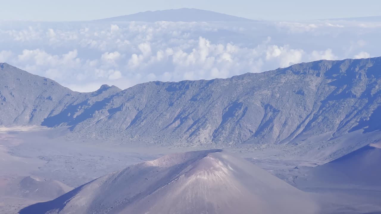 Cinematic booming up shot with foreground elements of the volcanic cinder cone craters at the summit of Haleakala on the island of Maui, Hawai'i