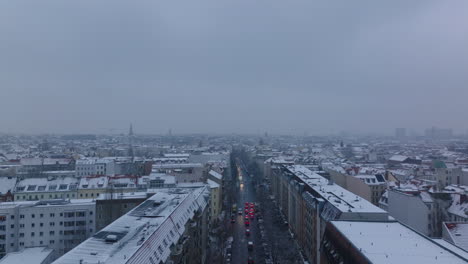 Rückwärts-Zeigen-Der-Schneebedeckten-Stadt-In-Der-Abenddämmerung.-Wenig-Verkehr-Auf-Den-Straßen.-Luftpanoramablick-Auf-Die-Großstadt.-Berlin,-Deutschland