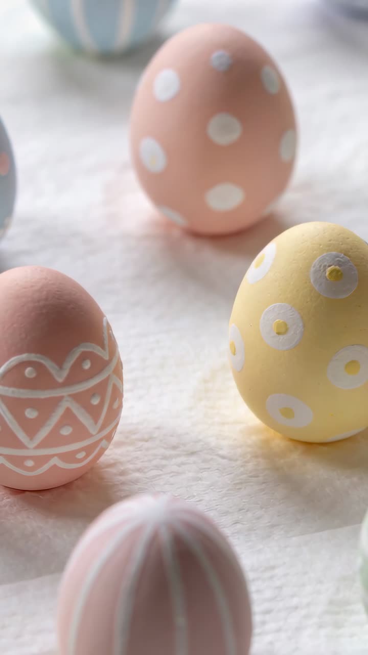 Vertical video: Pulling camera tightening frame on table with pastel eggs to highlight patterns