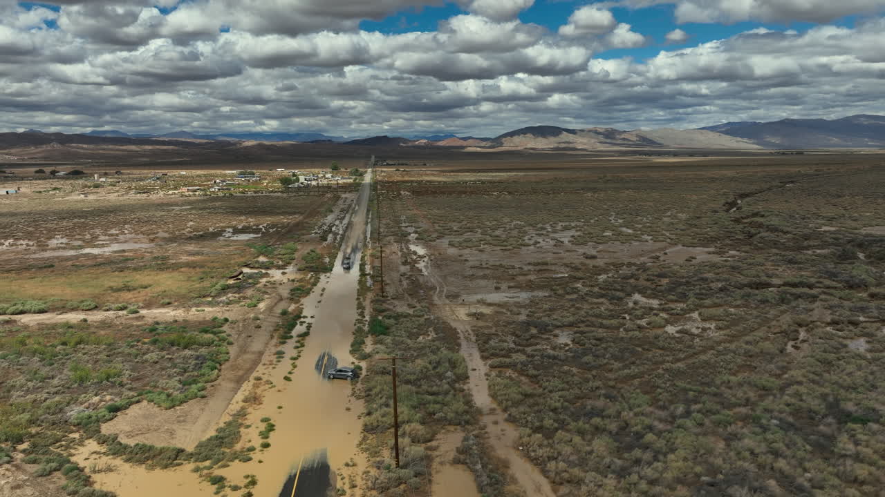 carretera inundada del desierto de mojave después de lluvias torrenciales fuera de temporada deja un vehículo varado - paralaje aéreo