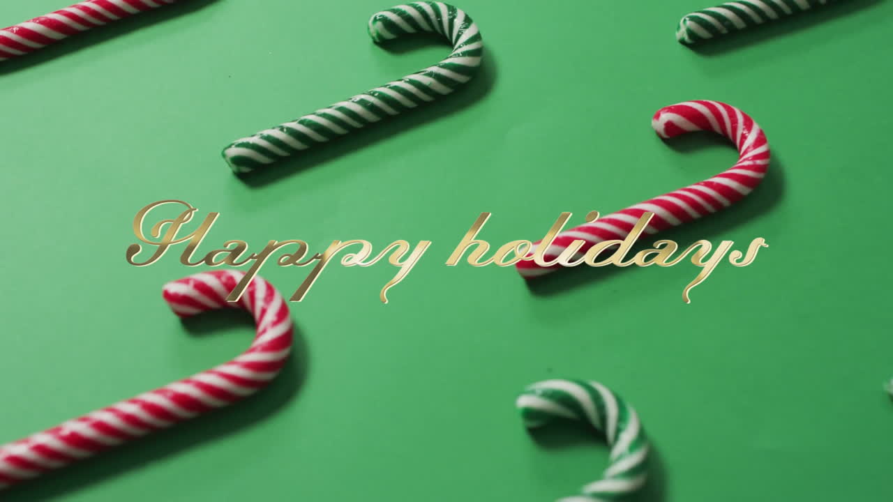 Animation of happy holidays text over candy canes on green background