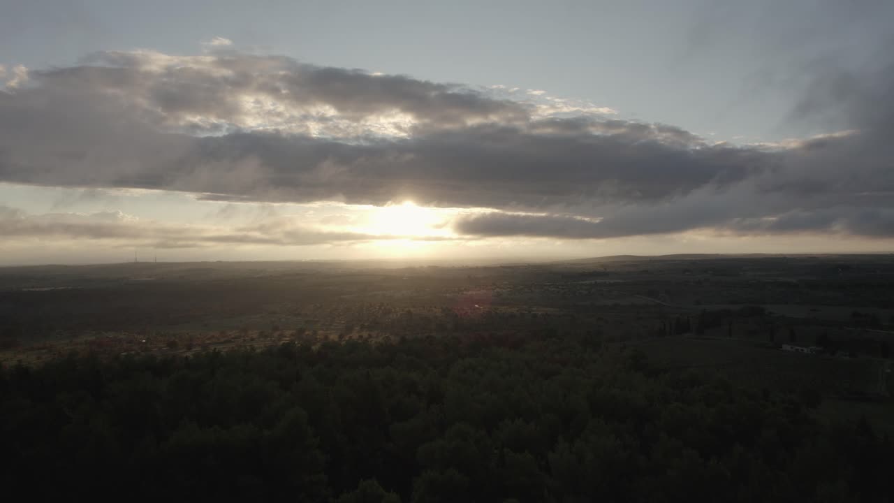 drone volando sobre un hermoso paisaje italiano con campos de cultivo y naturaleza con el sol rompiendo las nubes al amanecer en 4k