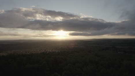 Drone-flying-over-a-beautiful-Italian-landscape-with-farmfields-and-nature-with-the-sun-breaking-through-the-clouds-at-sunrise-in-4k