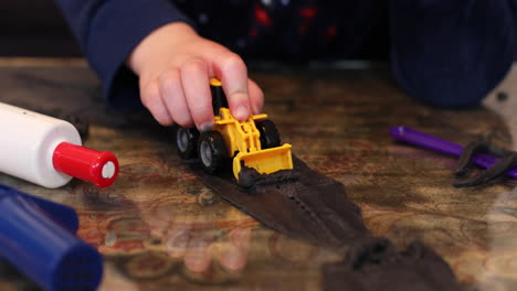 Un-Niño-Jugando-Con-Su-Excavadora-De-Remolque-Y-Arcilla-Adentro-Durante-El-Encierro