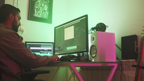 editor de video independiente sentado en su silla negra, manos escribiendo, editando videos en su escritorio en una habitación de niebla, con una chaqueta marrón beige, haciendo clic en su ratón