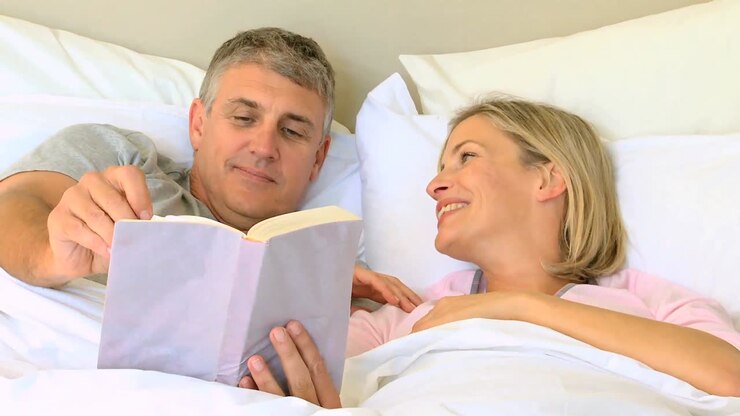 una coppia a letto che si gode un libro