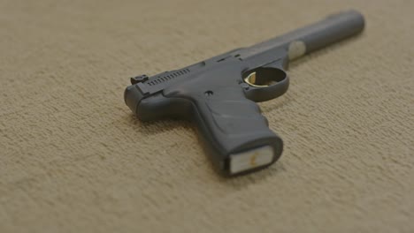 hand taking loaded handgun that lies on the floor