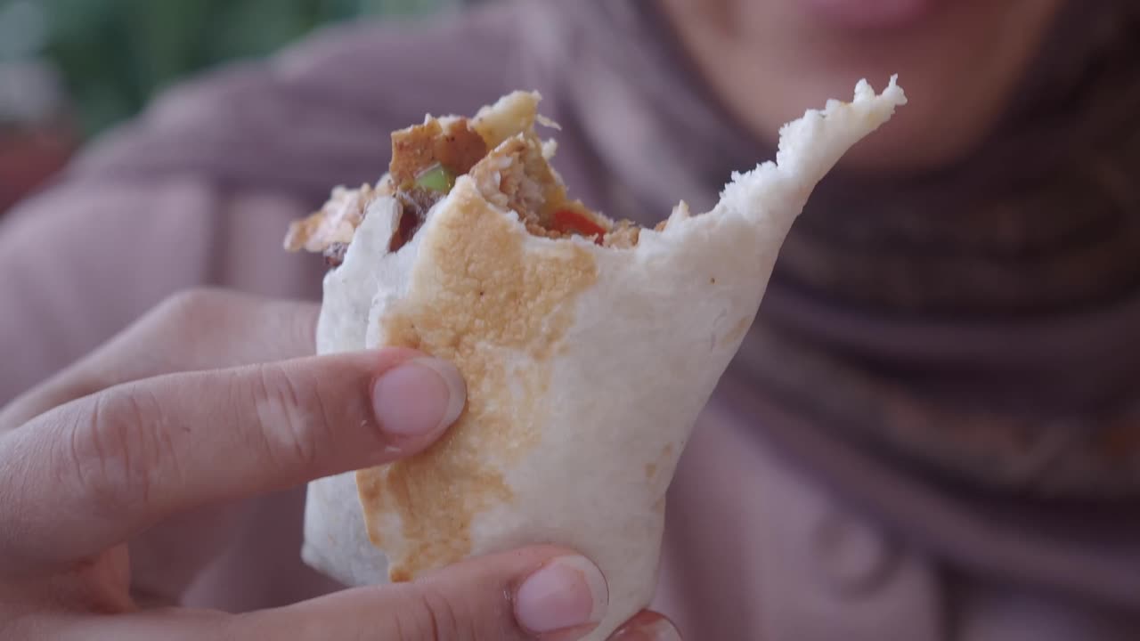 Close-up of a Hand Holding a Partially Eaten Shawarma Wrap