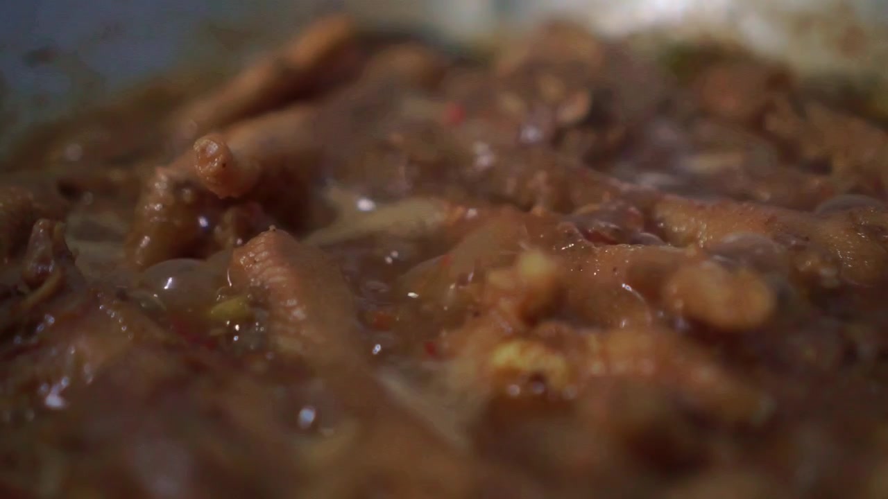 Primo piano di pollo in cottura in salsa bollente con spezie. Sugo caldo e ribollente che crea un saporito piatto fatto in casa