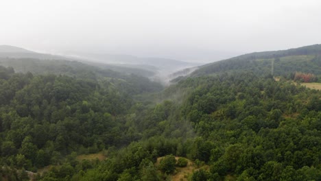 Drone-flight-over-green-hills-with-fog