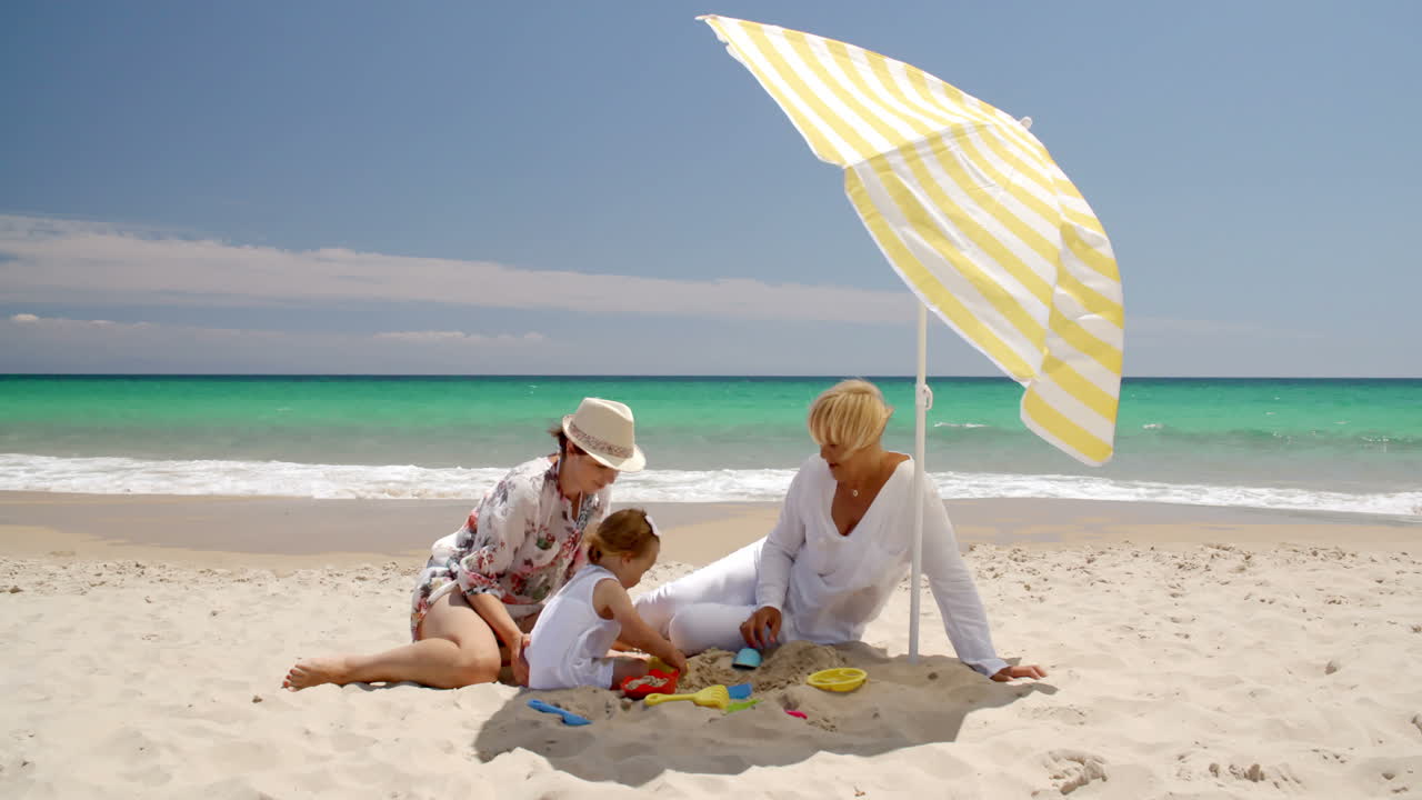 Grandma  Mom and Little Girl Playing at Beach Sand