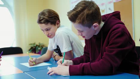 students studying at school. teenage boys sitting at the table and writing tasks in the modern classroom. educational process.