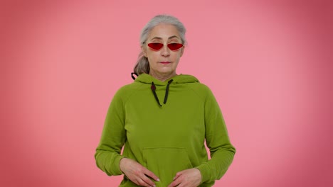 feliz lúdica elegante anciana abuela mujer con gafas de sol parpadeando el ojo, mirando a la cámara con una sonrisa
