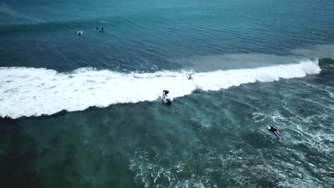 drone shot following two surfers at padang padang beach in bali, indonesia