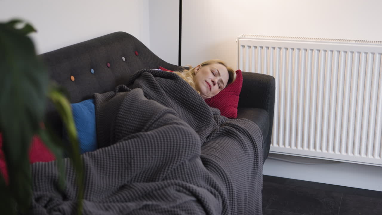 Kvinde sover på sofaen med et tæppe