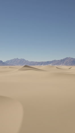 desert landscape with sand dunes and mountain range in the distance