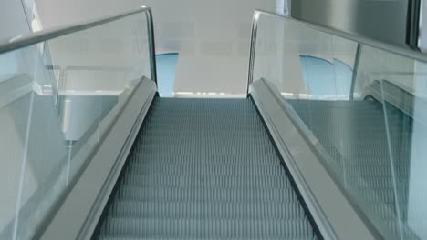 descending view of an empty escalator in a modern, bright building, giving a sense of quietness and motion