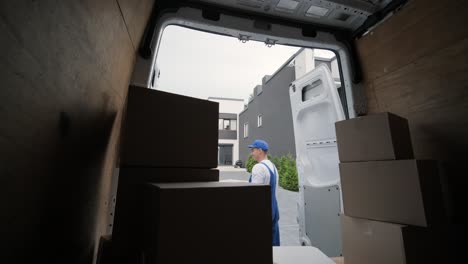 two young workers of removal company unload boxes from minibus into customer's home