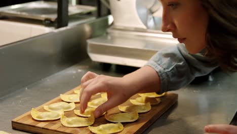 female baker arranging ravioli pasta in bakery shop 4k