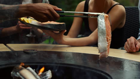 man hands putting fish slice on grill