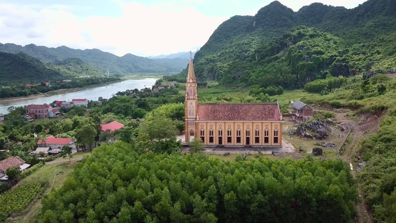 A christian church in Vietnam next to a river surrounded by an epic landscape