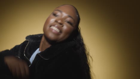 head and shoulders studio portrait shot of young woman dancing in spotlight against yellow background 3