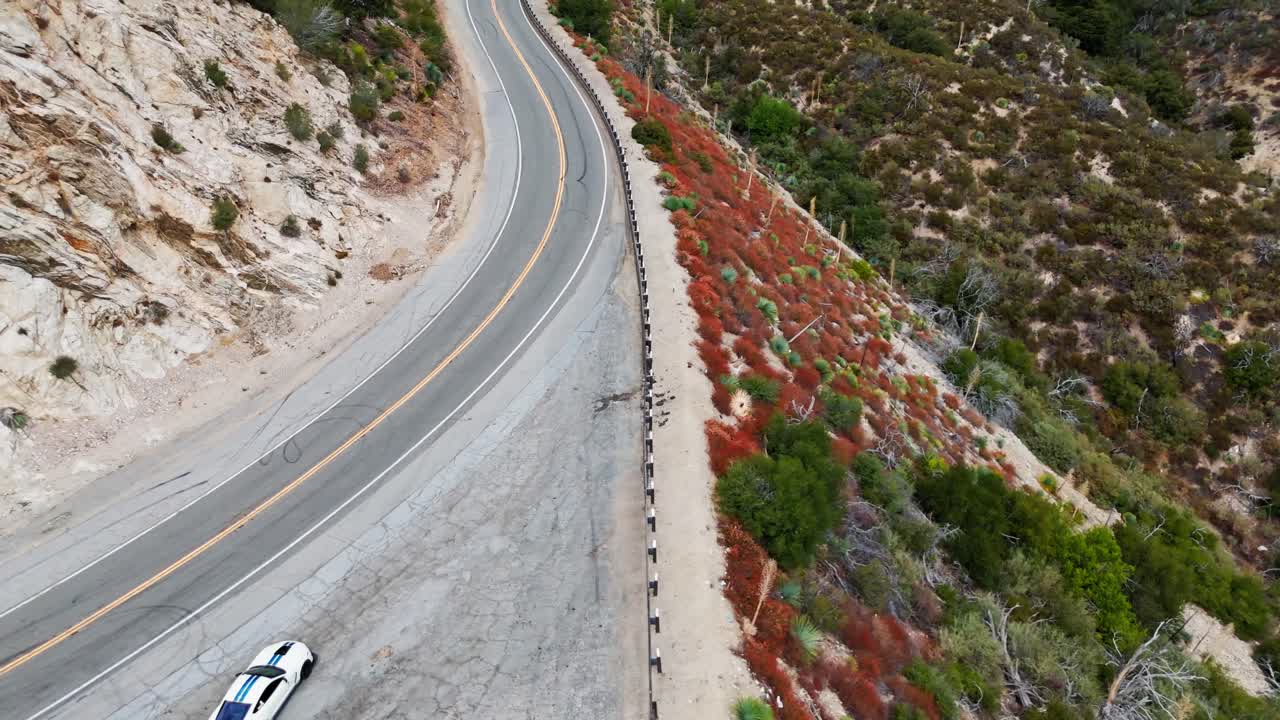 Drone shot of a car driving through the canyons and mountains of Angeles National Forest near LA