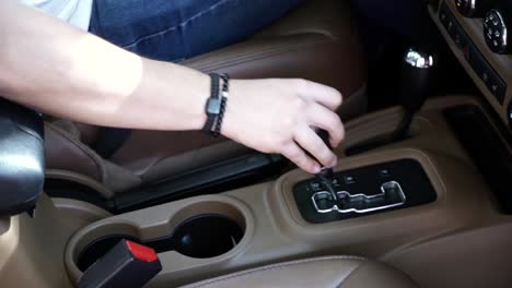 slow motion shot of a man's arm and hand changing gear in an automatic car