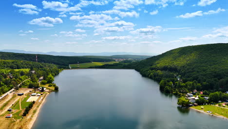 lake by rolling hills. clear blue skies reflect over a tranquil lake set against lush green hills and charming countryside homes
