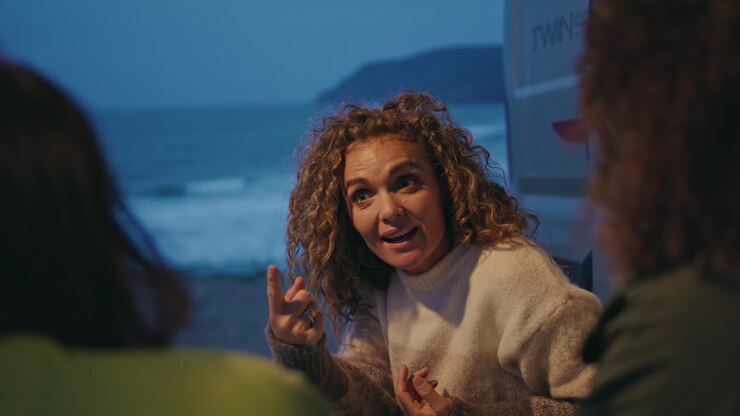 Positive friends talking camp place on evening ocean shore close up. Happy woman