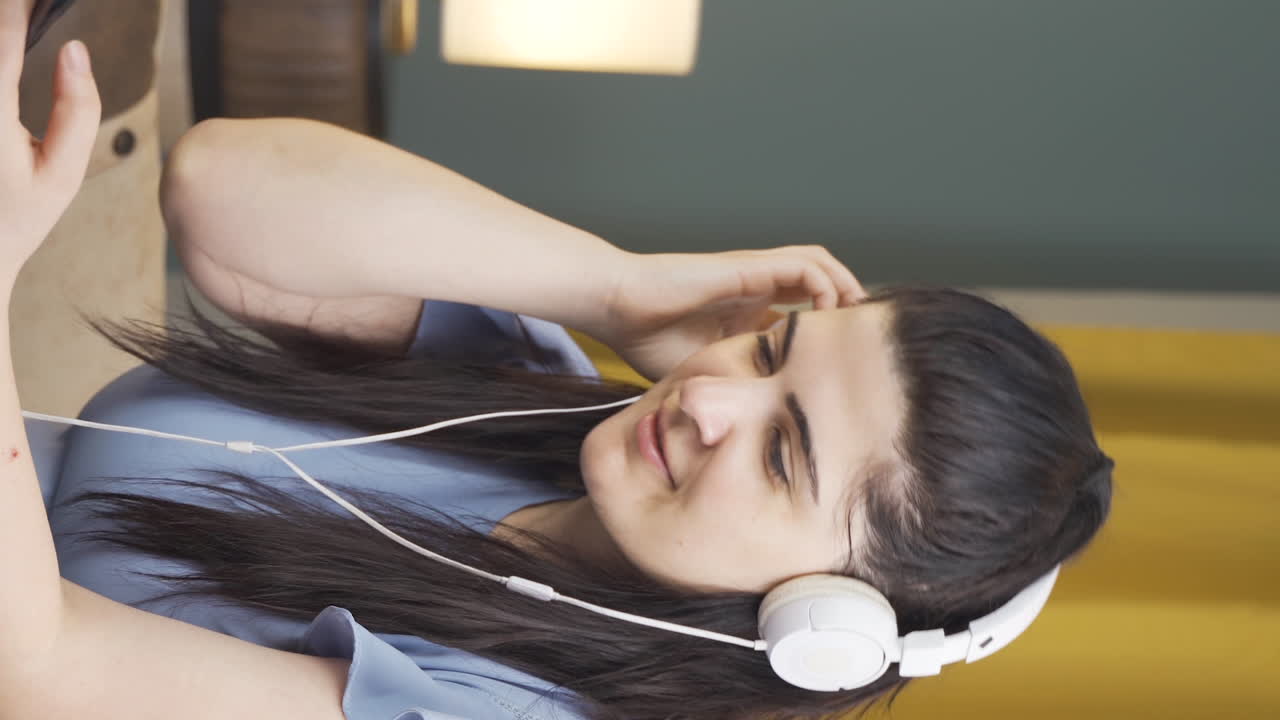 video vertical de una mujer feliz escuchando música con auriculares.