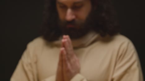 close up shot of man wearing robes with long hair and beard representing figure of jesus christ blessing bread and wine