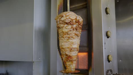 chicken shawarma skewer hanged on grill turning around on fire