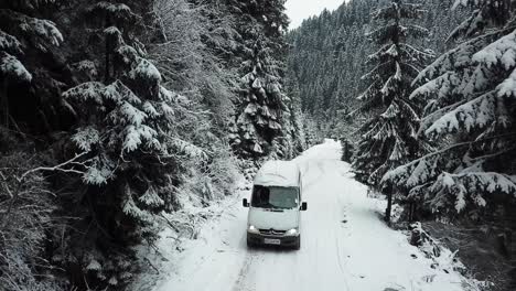 black car driving on snowy road through winter forest black car driving on snowy road through a forest in winter