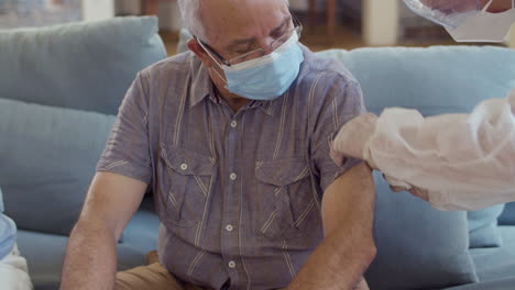 Medium-shot-of-female-doctor-vaccinating-senior-man-at-home