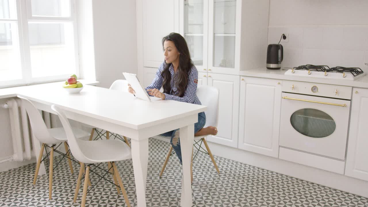 Beautiful woman relaxing with tablet in kitchen