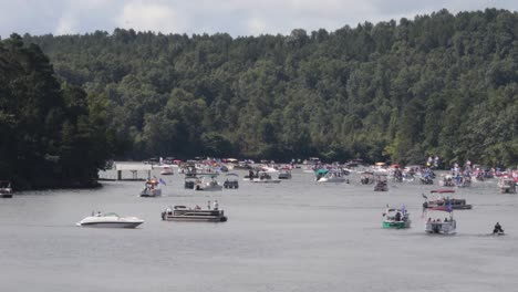 numerous boats gathered on a lake surrounded by dense forests under a cloudy sky