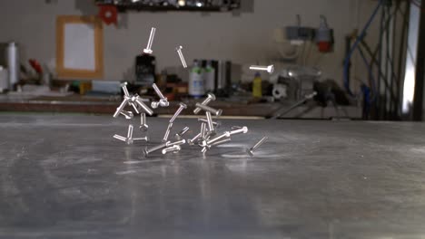 tornillos cayendo sobre una mesa de metal en una tienda de metal