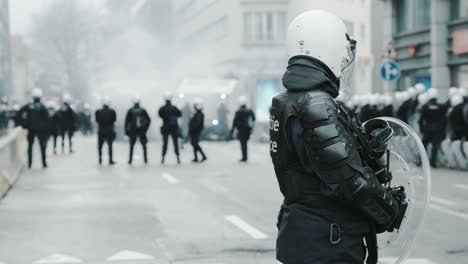 cinematic shot of unrecognizable police officer in full gear protecting the street with his unit during riots