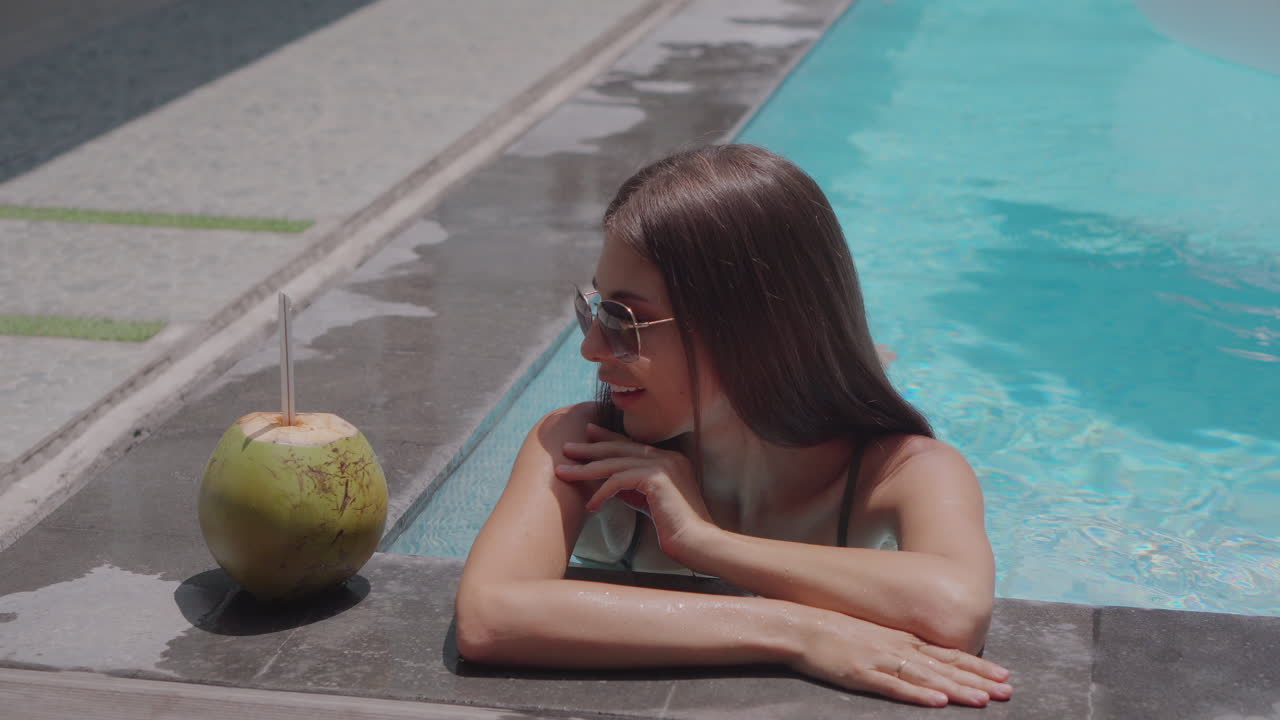 Woman Relaxing by the Pool with Coconut Drink