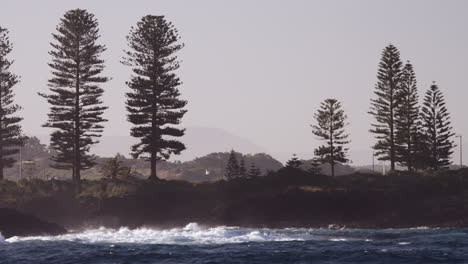 waves break onto the rocky shoreline of a small coastal town