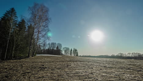 Sun-sinks-into-horizon-on-a-winter-day,-frozen-meadow-in-Europe,-timelapse