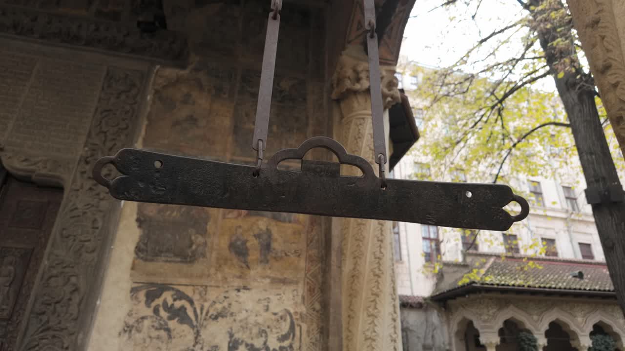 Ancient wooden semantron hanging beneath carved columns in the quiet monastery courtyard