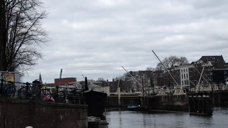 Zoom-in-on-a-boat-throughway-in-Amsterdam-on-the-canal,-as-a-bird-flies-by-with-bikes-and-boats-and-houses-nearby