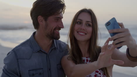 young happy caucasian couple taking photo using smartphone enjoying romantic sunset on beach together slow motion