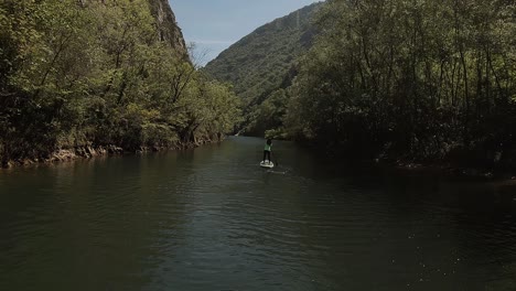 shot from behind of a young girl stand up paddling along a canyon