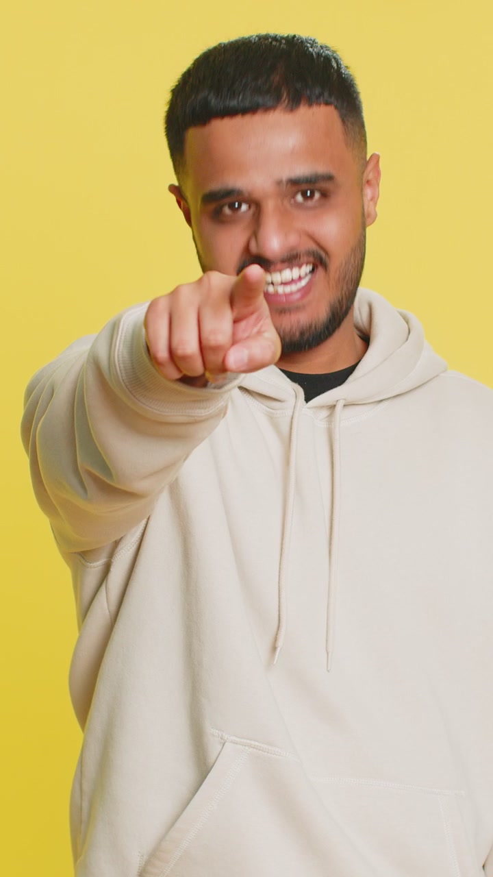 Glad indisk smilende mand peger fingre mod kameraet og laver et vinder-valg ved at vise, hvilken vej man skal vælge