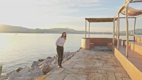 carefree young woman plays by the sea while waiting during golden hour