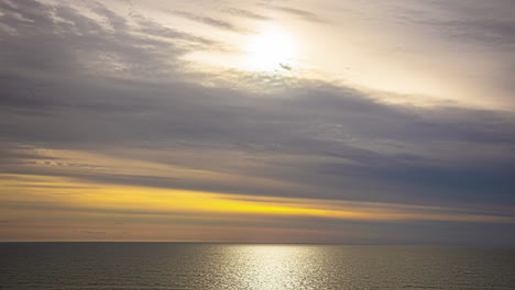 Zeitraffer-Des-Sonnenlichts-Am-Späten-Nachmittag,-Das-Durch-Treibende-Wolken-über-Dem-Meer-Dringt,-Mit-Gelbem-Himmel